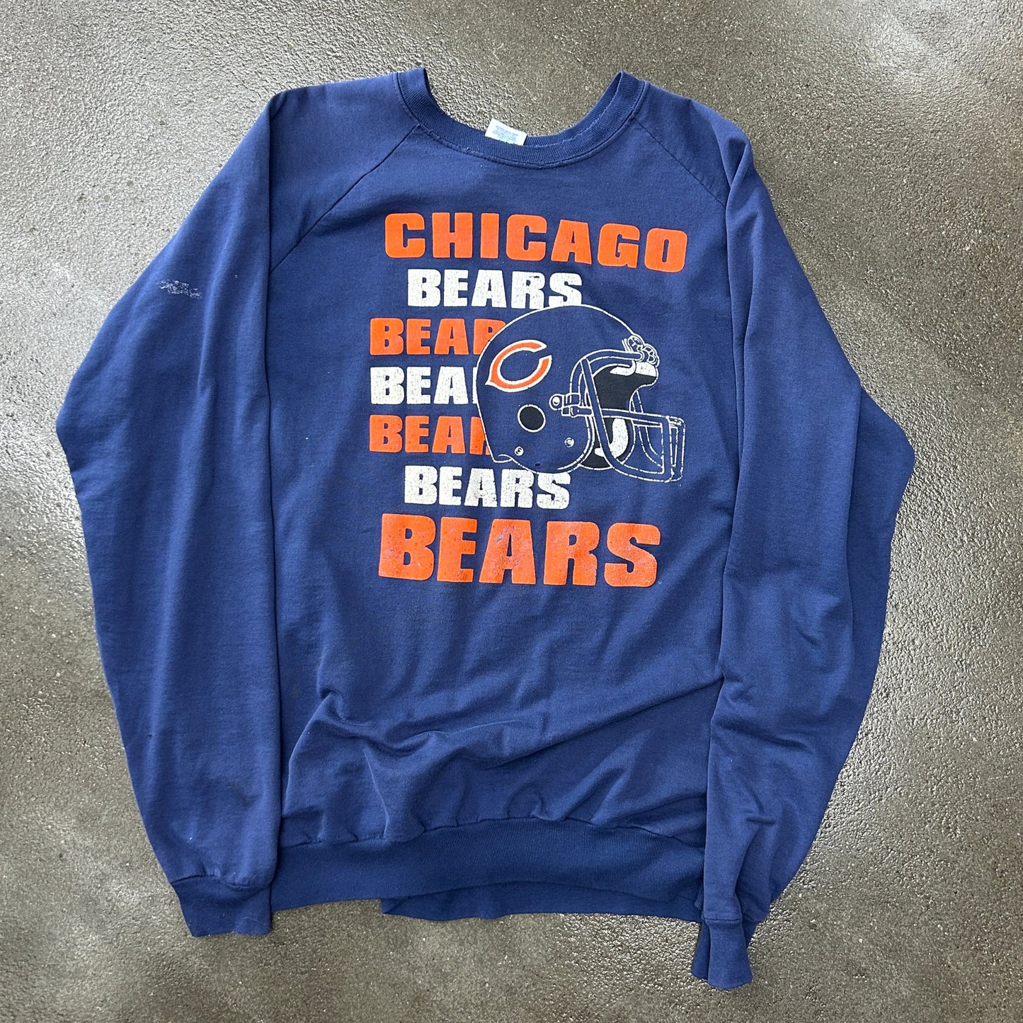 Blue sweatshirt with Chicago Bears graphics on a gray concrete surface
