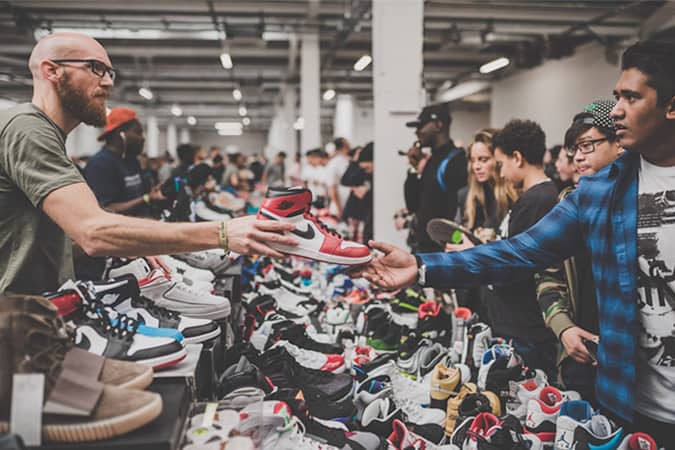 men selling sneakers to each other at a sneaker event around a table of shoes