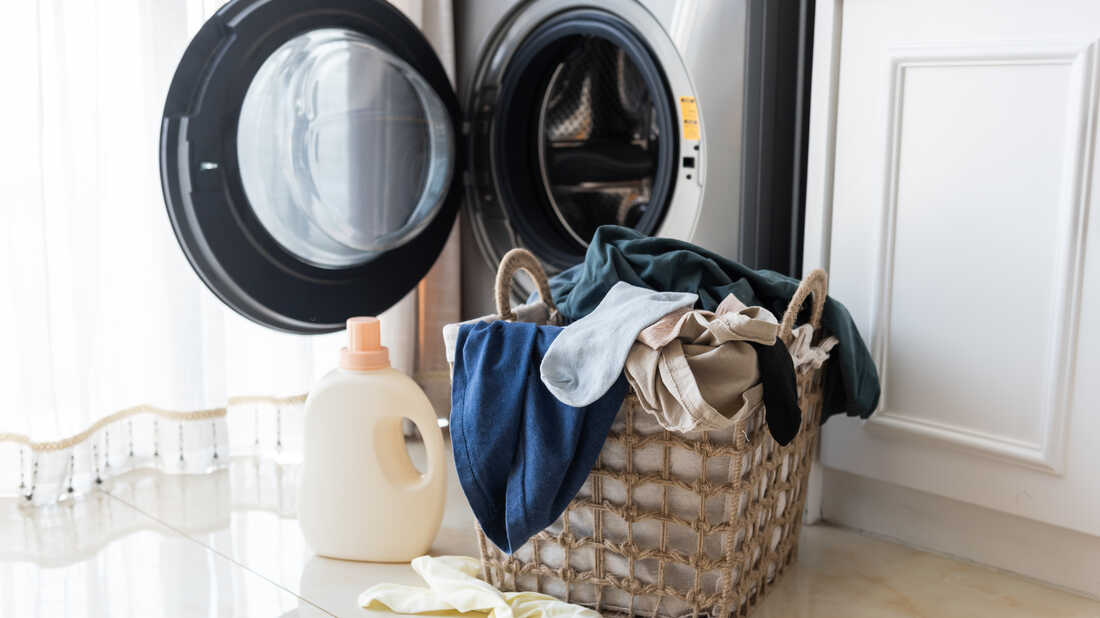 a basket of laundry, with detergent in front of a washing machine