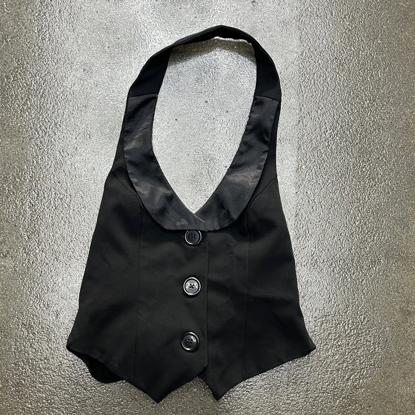 Black waistcoat with buttons on a textured gray background